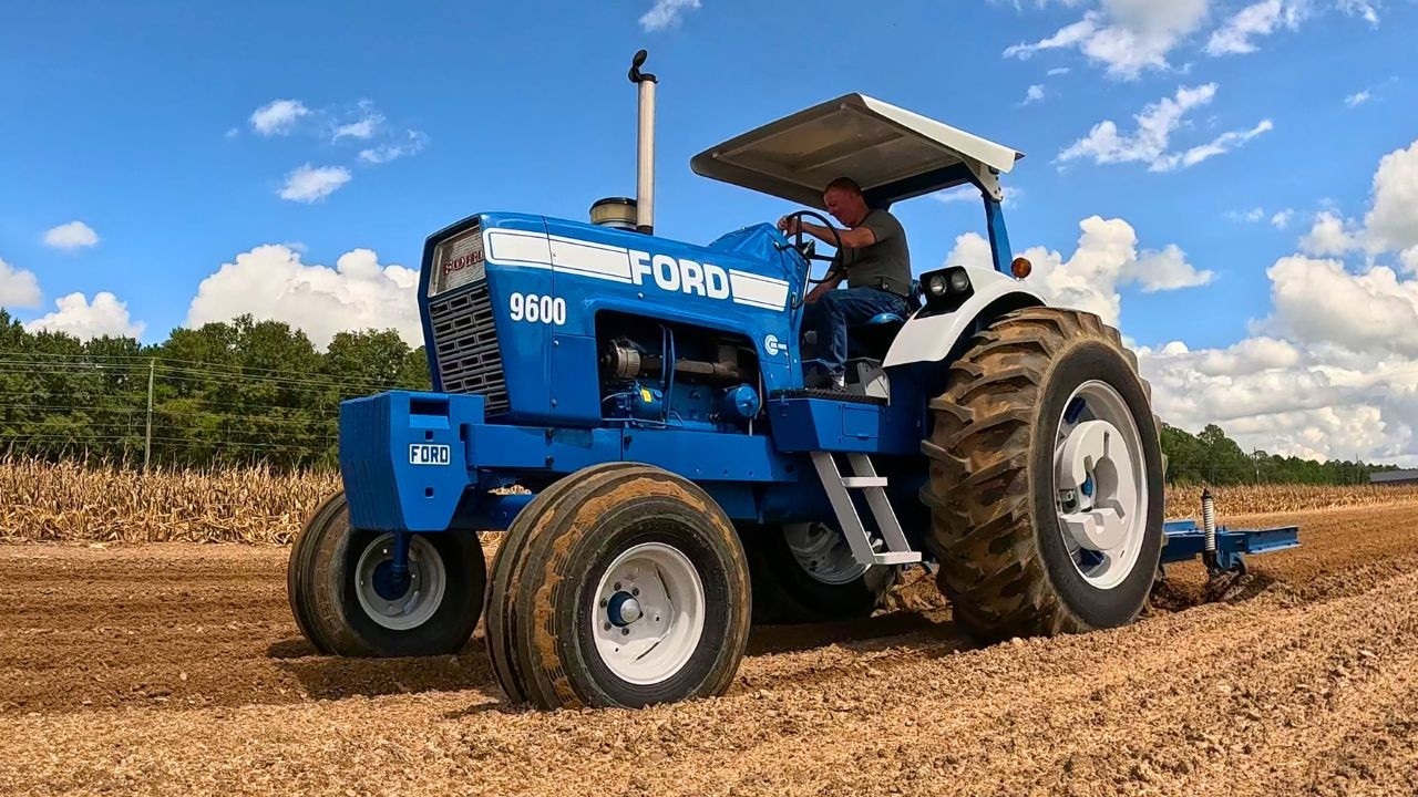 A blue Ford tractor plowing a field